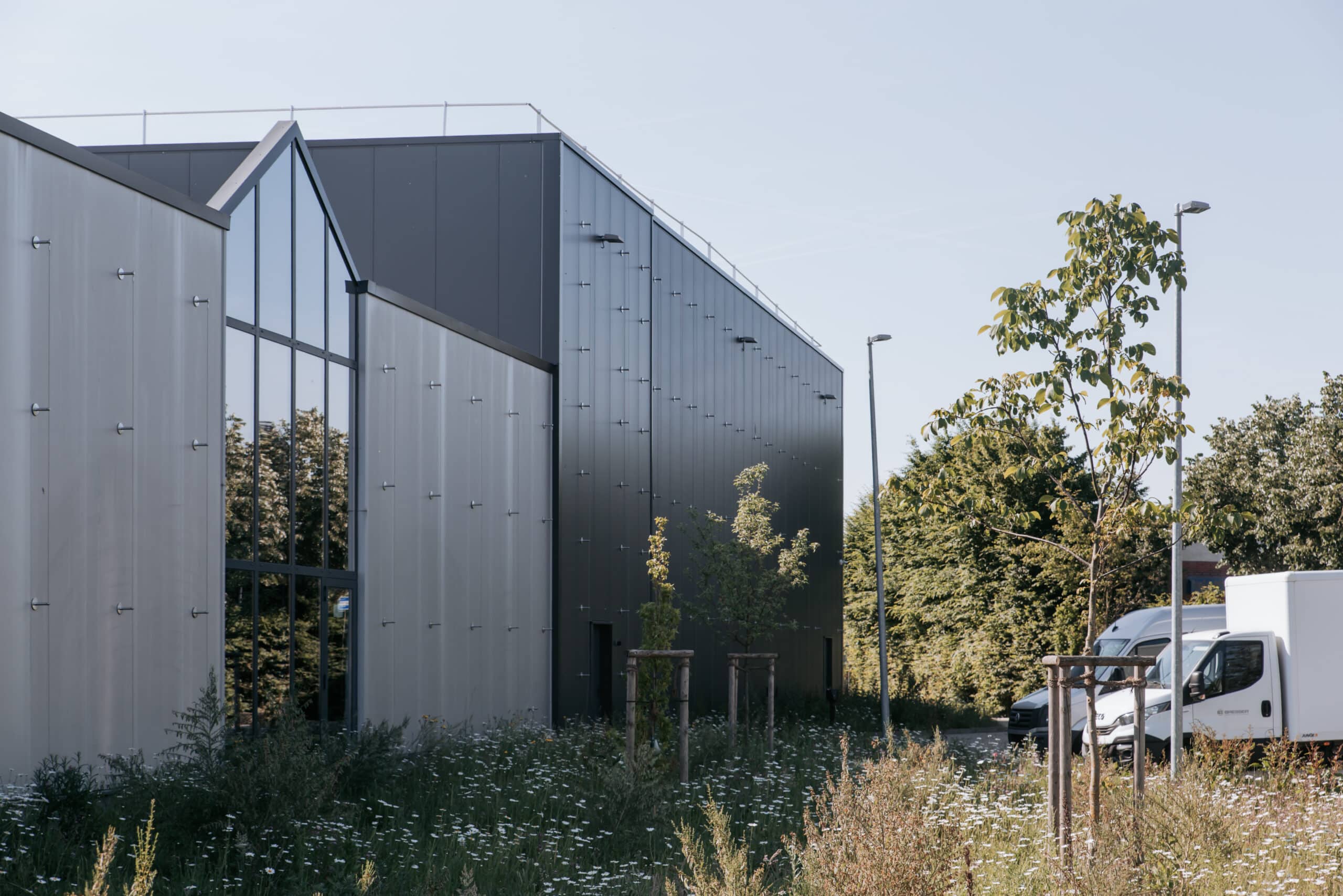 Seitenansicht der Lagerhalle mit Metallfassade und begrünter Außenfläche.