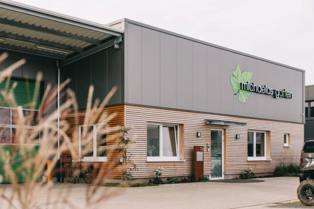 Seitenansicht des Bürotrakts mit Holzfassade und Firmenlogo von Michaelas Garten.