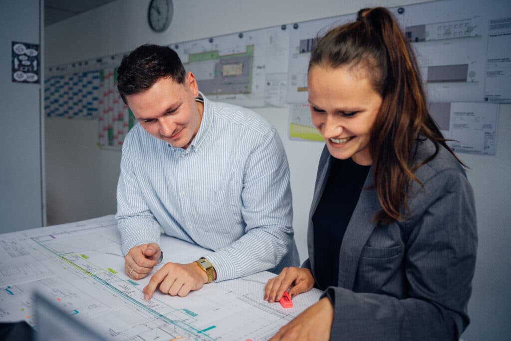 Mitarbeitende von GIESERS BAU über Zeichenplänen