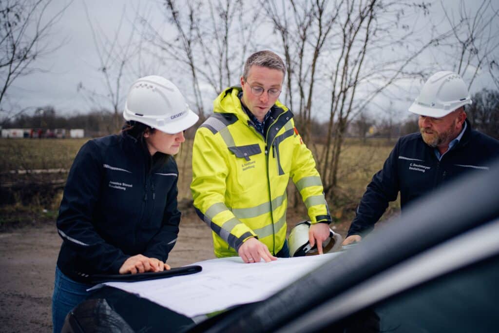 Mitarbeitende von Giesers Stahlbau GmbH auf einer Baustelle, die sich Baupläne ansehen
