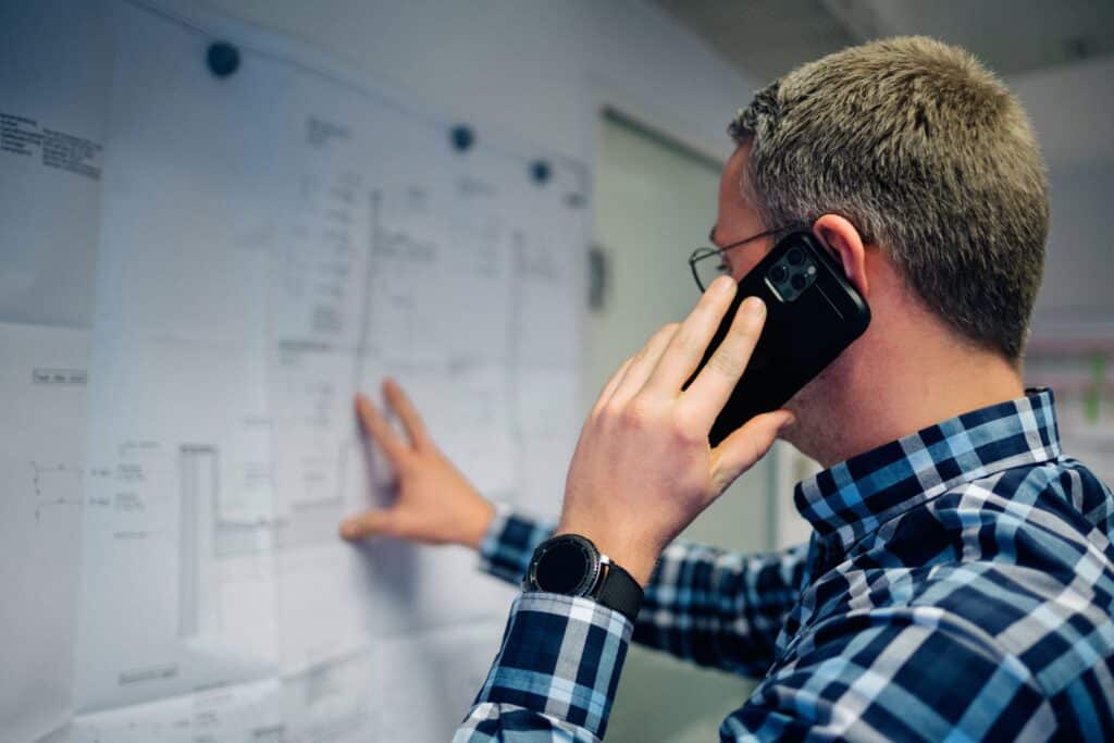 Mitarbeiter von Giesers Stahlbau GmbH telefoniert und schaut sich Detailpläne an