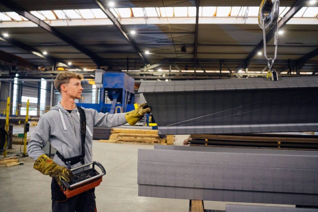 Ein Mitarbeiter von Giesers Stahlbau GmbH in der Werkstatt, beim bedienen von Maschinen zur Bewegung von Stahlbalken