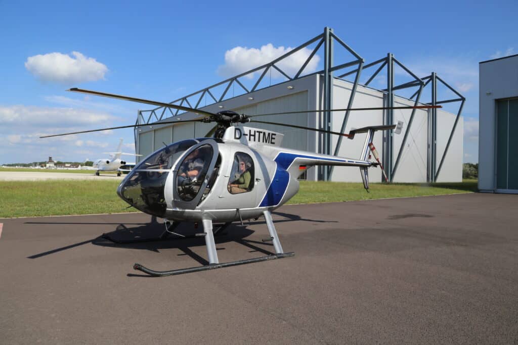 Außeansicht eines Hangars mit einem Helikopter im Vordergrund