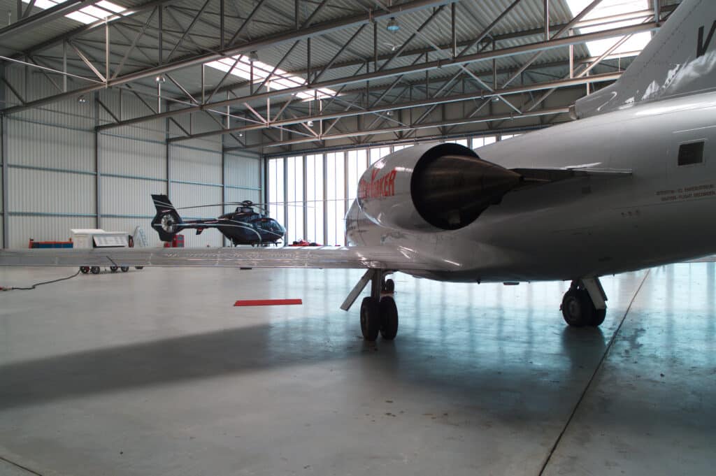 Innenansicht eines Hangars mit Helikopter und Privatjet
